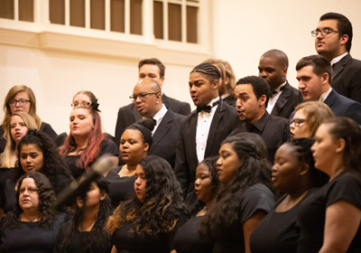 Choir members dressed in all black are pictured singing