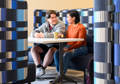 Two students sitting at a table in a blue colored booth
