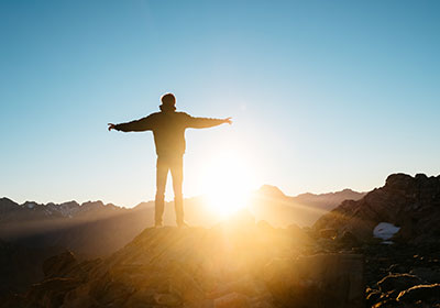 Photo of person facing sunrise with arms spread wide|Photo of person facing sunrise with arms spread wide