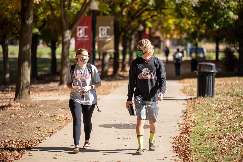 A female and male student walk on Bridewater's campus wearing masks