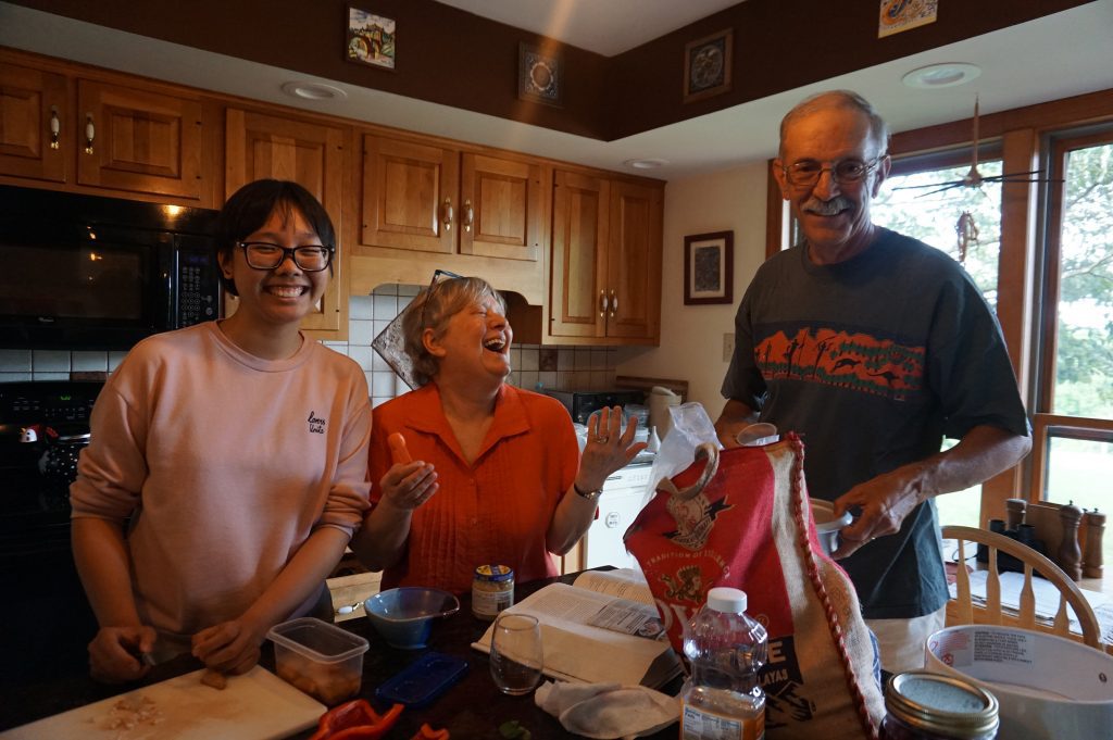 Anh Nguyen stands in a kitchen with Sharon Kalbarczyk and her husband Sam Zigler