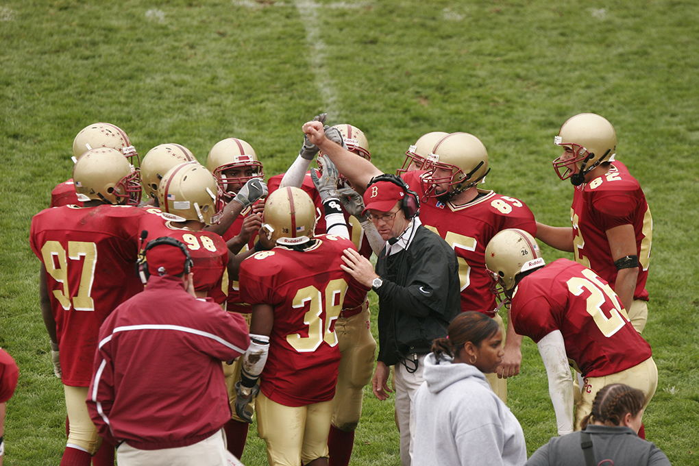 group of football players surrounds a coach