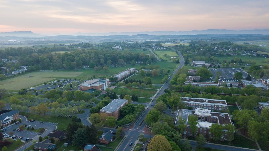 An aerial view of Bridgewater College's campus with the sun rising in the background