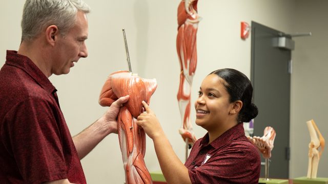 Student pointing to muscle in health and exercise science class