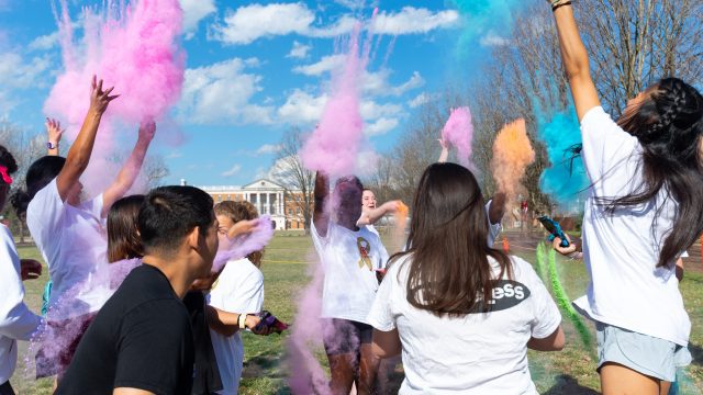 Students throwing bright pink and blue chalk in the air