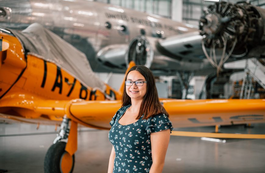 Bridgewater College student Jen Chan pictured at her internship site, Dynamic Aviation in Bridgewater. She is smiling and a plane is visible behind her.