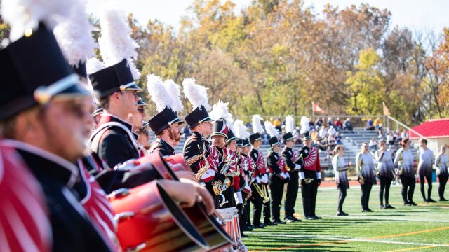 Members of the Marching Band standing in a line on the football field during a performance