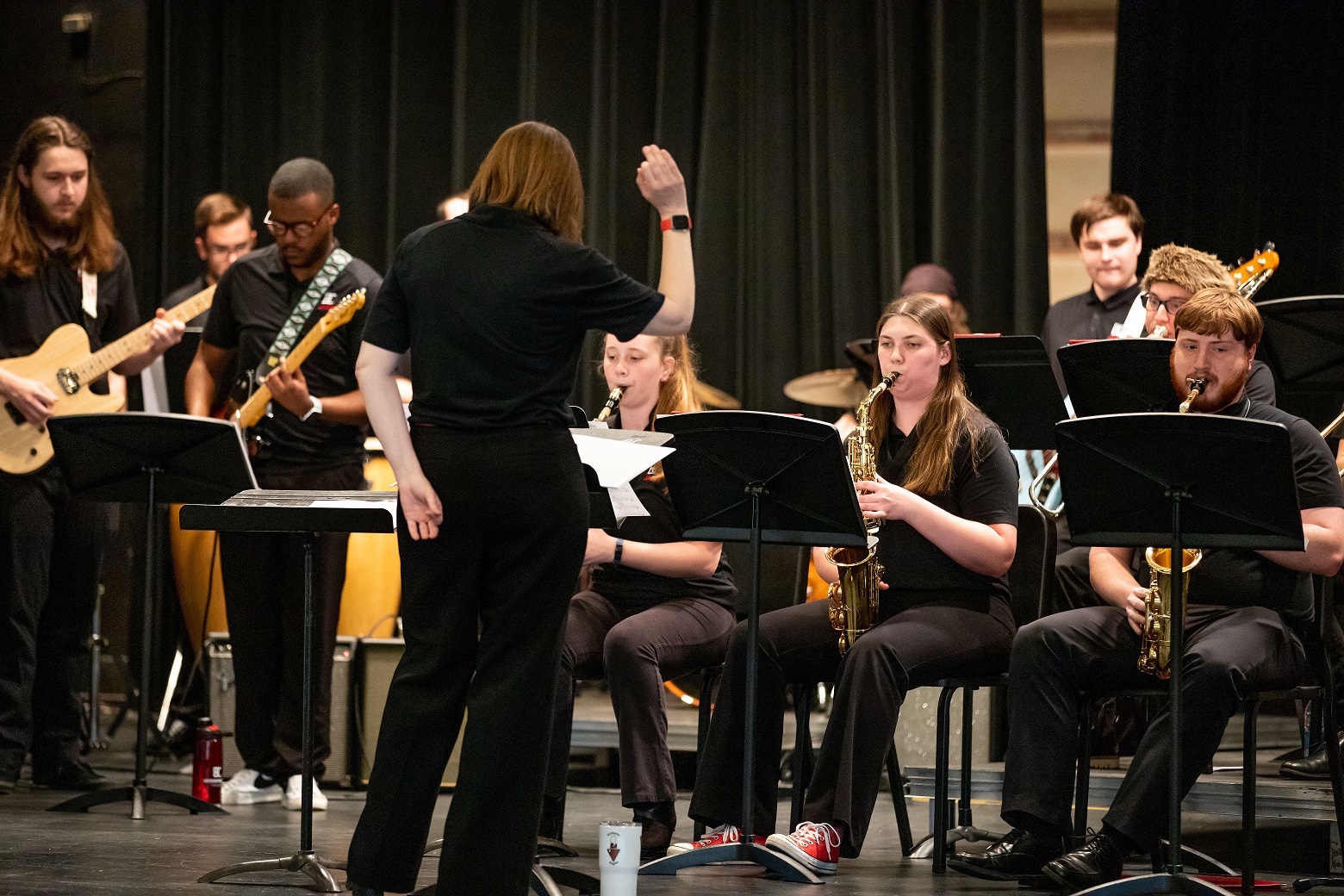 a female conductor stands before a jazz ensemble