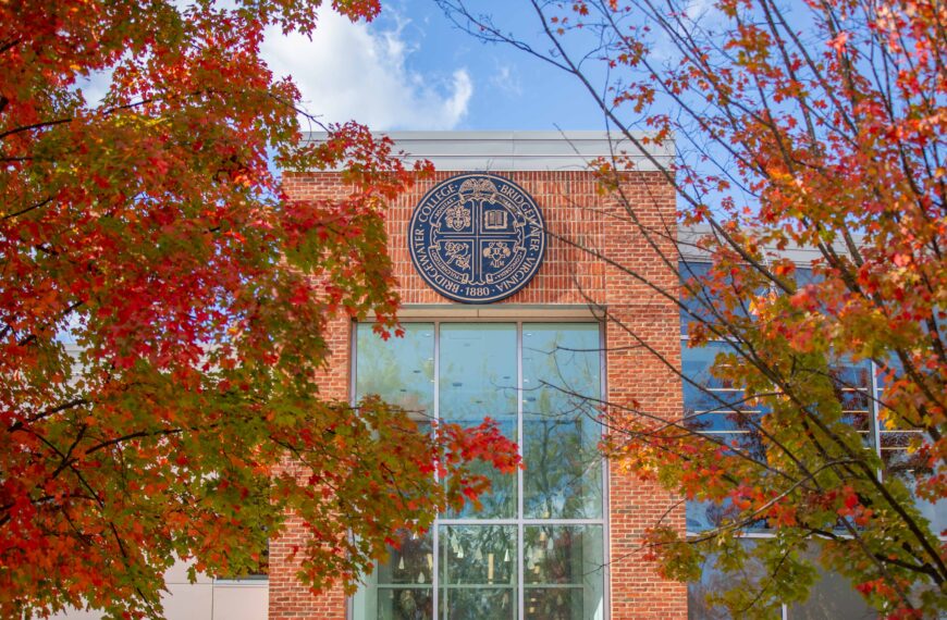 The exterior of the Forrer Learning Commons that shows the Bridgewater College seal. Trees with fall leaves surround it.