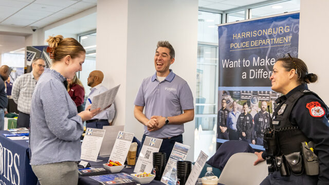 Student speaking with members of the Harrisonburg police department at a career fair