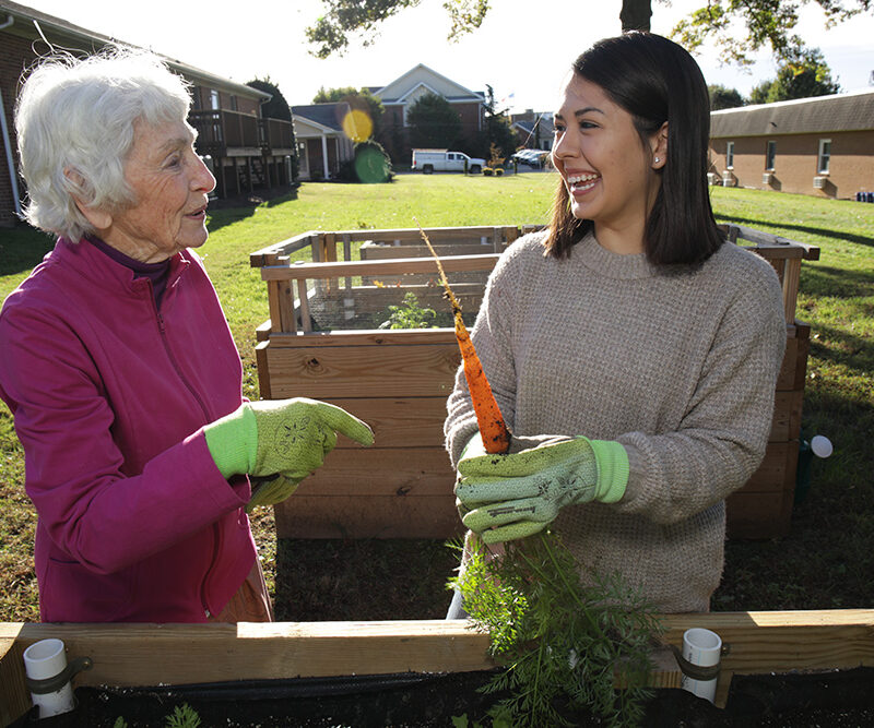 Student working in a garden with an elderly woman