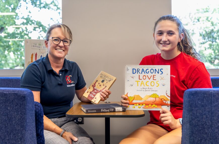 A professor and student holding books and smiling