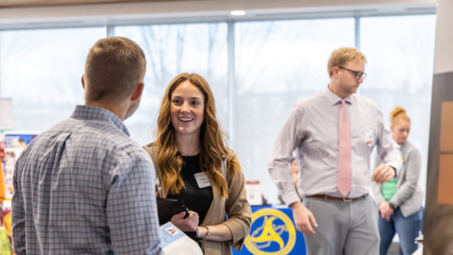 student with long red hair talking to recruiter at a career fair