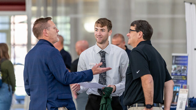 Group of men talking with each other at the career fair