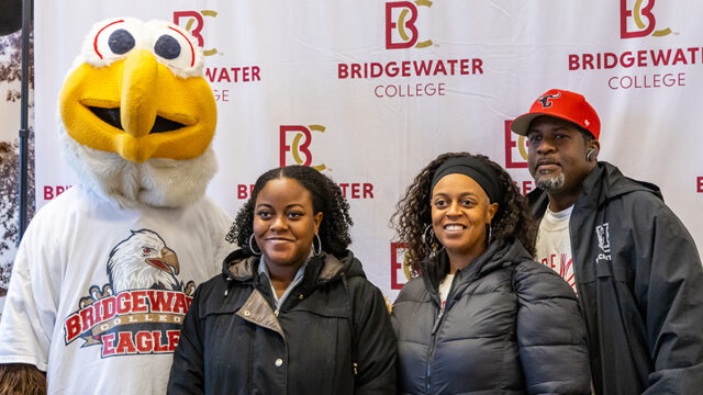 Family posing with Ernie the Eagle in front of b-C logo backdrop