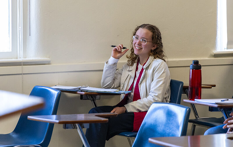 Student sitting at a desk in class taking notes