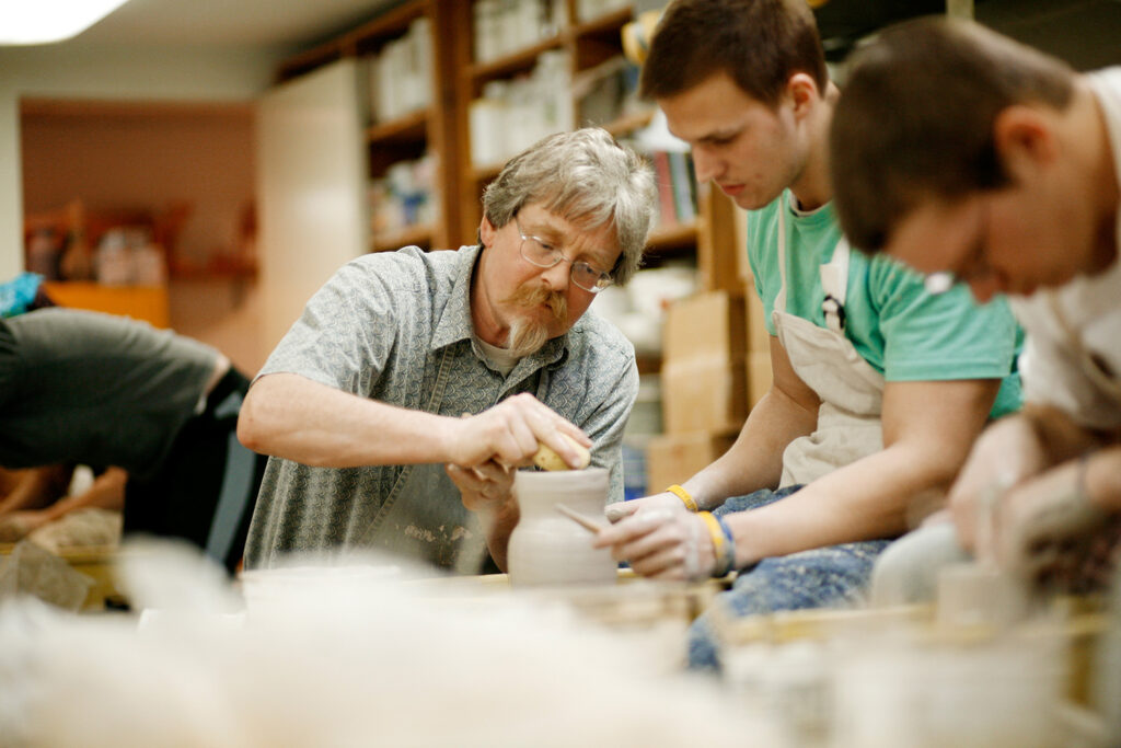 Professor Michael Hough working with student at pottery wheel