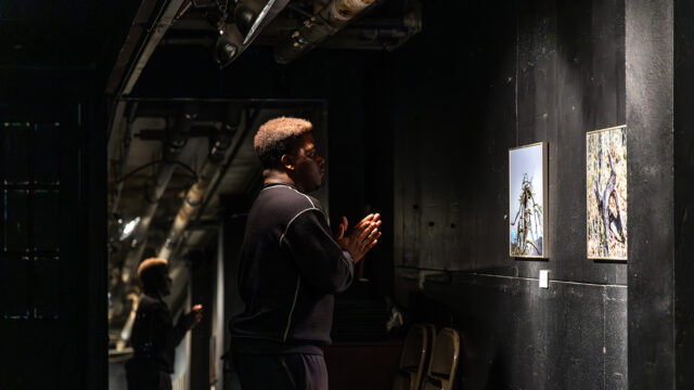 Student viewing his black-and-white photography prints on display in gallery setting