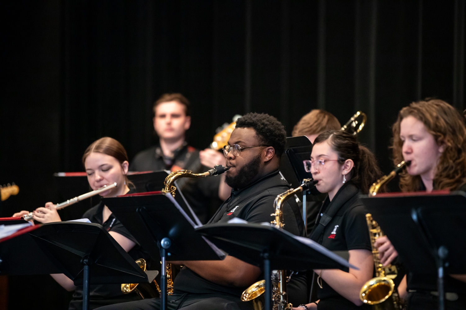 jazz_band_spring_concert_057 Three people sitting behind music stands playing saxophone