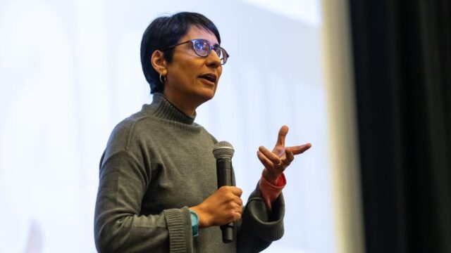 Irshad Manji speaks fervently in front of a screen