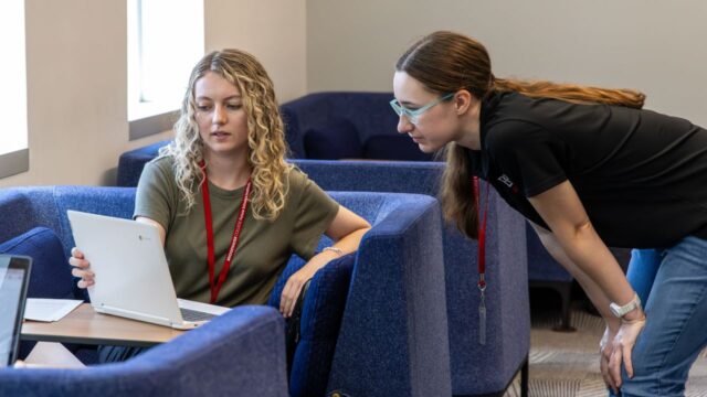 Two students work together on a laptop